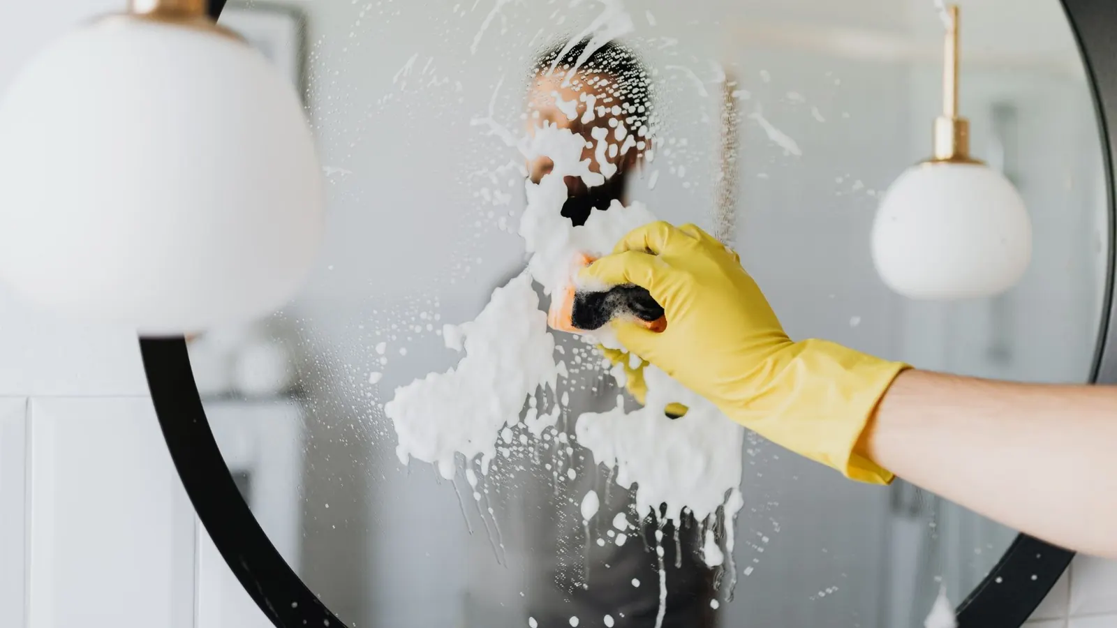 Hand scrubbing a bathroom mirror during Lara Cleaning Services house cleaning in Palm Springs CA